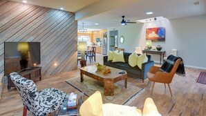 Un salon moderne avec un plancher en bois, un canapé, une table basse et un téléviseur.