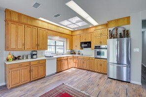 Una cocina con armarios de madera, un refrigerador de acero inoxidable y un microondas.