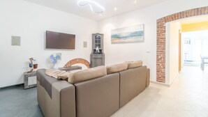 Una sala de estar moderna con un sofá, un televisor de pantalla plana, un ventilador y un cuadro en la pared.