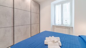 Un dormitorio con cama, ventana con cortinas y un radiador.