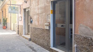 Un edificio con fachada de piedra, una puerta con panel de vidrio y un pequeño espacio exterior con una planta en maceta.