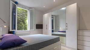 Un dormitorio con cama, ventana, espejo y armario.