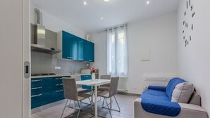Un espacio habitable compacto con kitchenette, comedor y sofá.