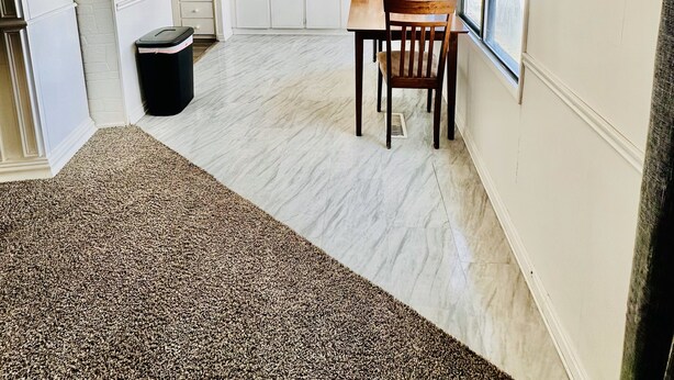 Uma cozinha ampla com armários brancos, uma área de jantar com mesa e cadeiras, um ventilador de teto e uma janela grande com vista.