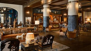 A spacious lobby with a bar area, leather seating, and a large chandelier. - Bowie House, Auberge Collection (Fort Worth)