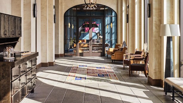 A spacious lobby with a large chandelier, arched windows, and a patterned rug. - Bowie House, Auberge Collection (Fort Worth)