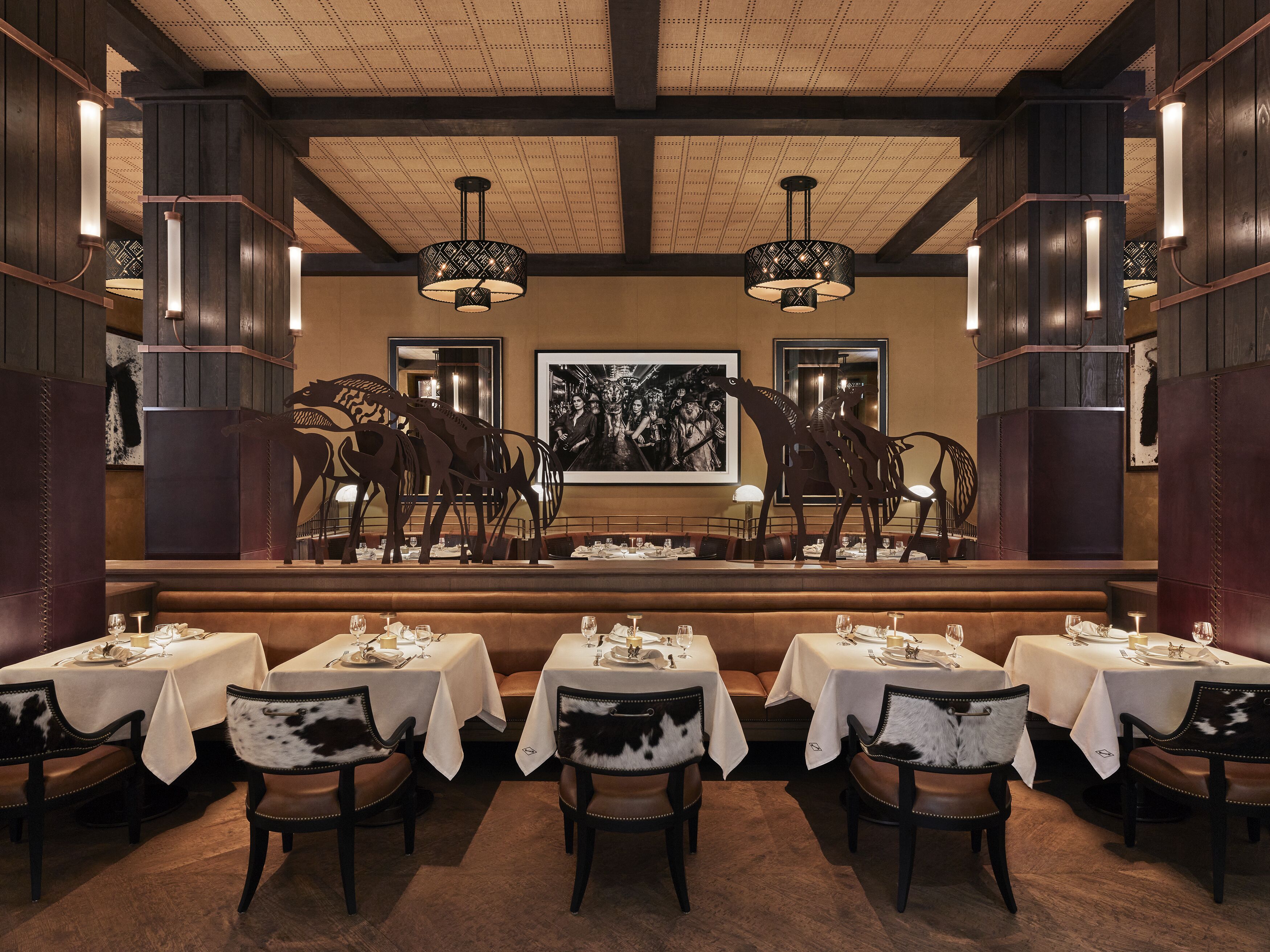 Un restaurante con paneles de madera, manteles blancos y sillas con estampado blanco y negro.
