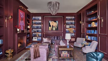 A library with bookshelves, a fireplace, and a sofa.