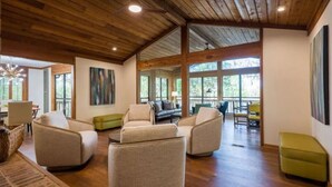 Un vaste espace de vie doté de plafonds en bois, de grandes fenêtres et de sièges confortables.