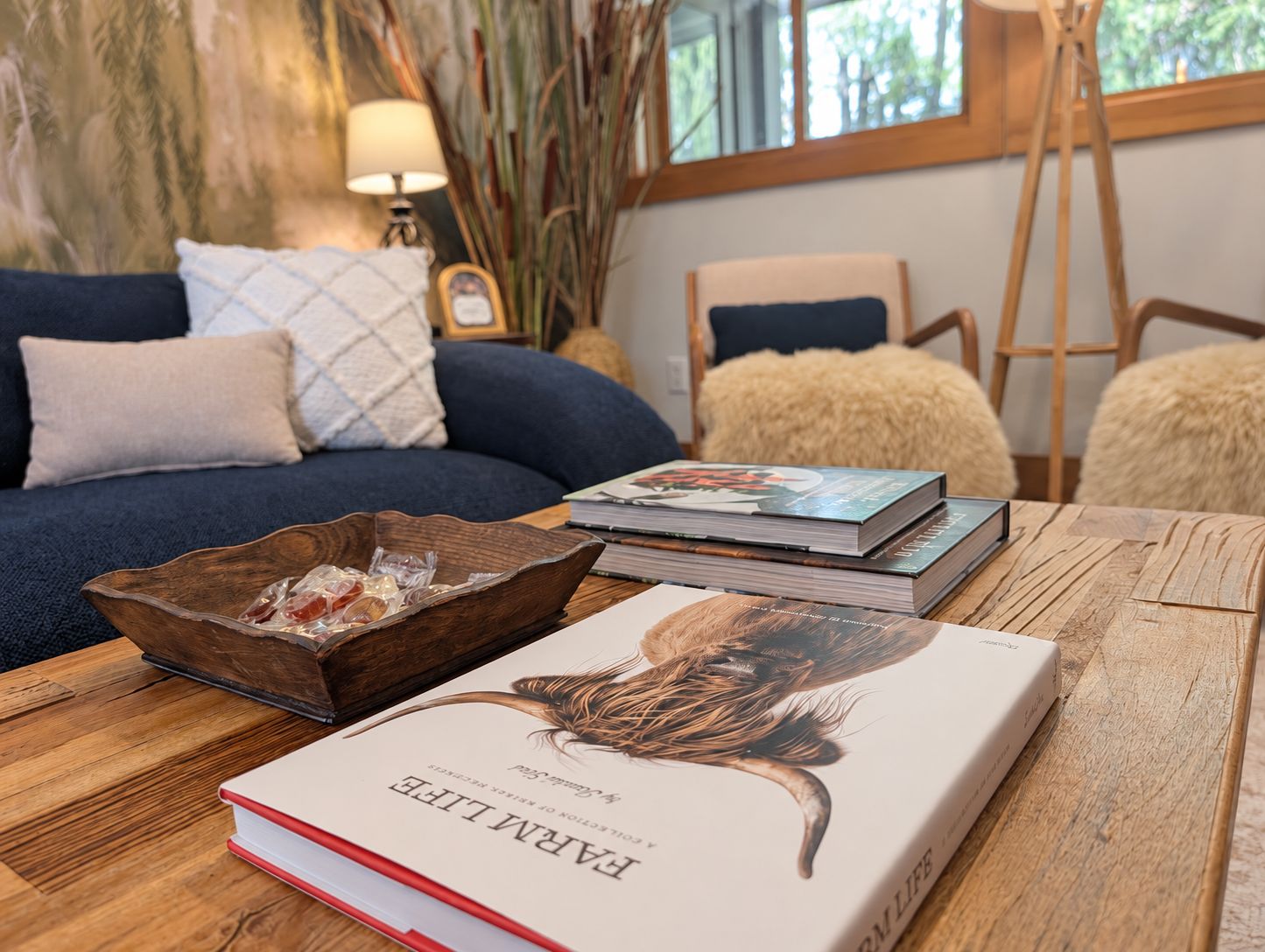 Una habitación con una mesa de madera, un libro titulado 'EARTHLIFE' y un sofá azul con cojines.