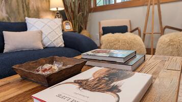 Una habitación con una mesa de madera, un libro titulado 'EARTHLIFE' y un sofá azul con cojines.