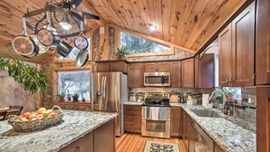 A kitchen with wooden cabinets, granite countertops, stainless steel appliances, and a large window. - Panoramic Catskills Farmhouse and Spa (Harpersfield)