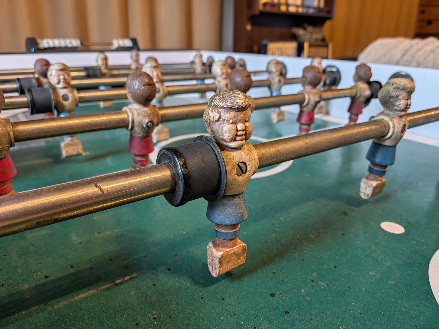 A close-up of a foosball table with metal rods and wooden figures.