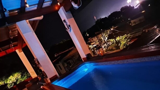 Une vue nocturne d’une piscine avec une terrasse en bois et une vue sur les environs.