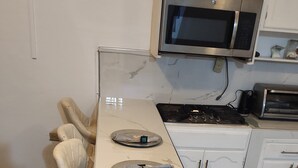 Une cuisine dotée d’un plan de travail blanc, de deux appareils en acier inoxydable et d’un revêtement de sol en bois.
