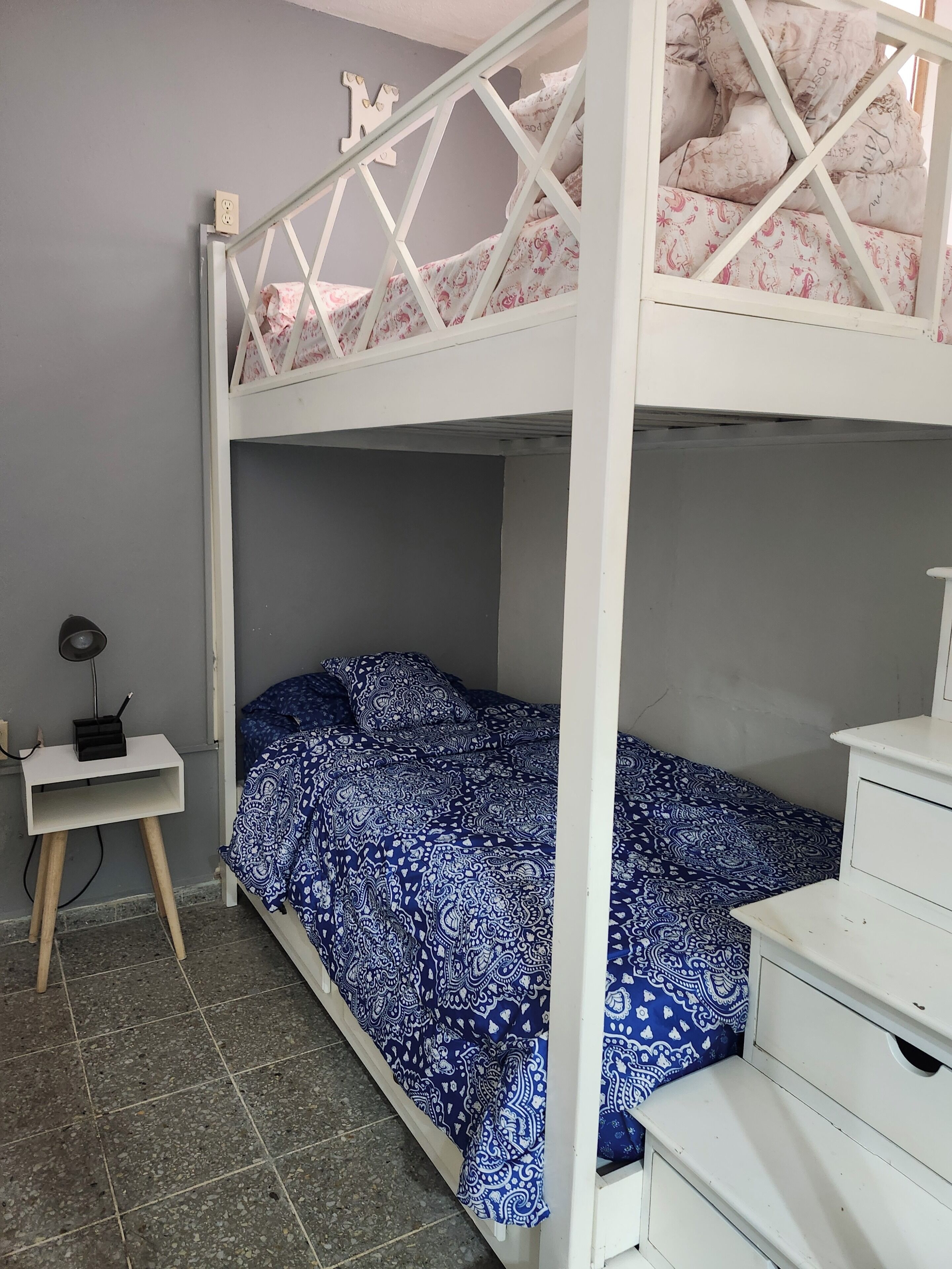 Una cama individual sobre otra y un escritorio con una lámpara.