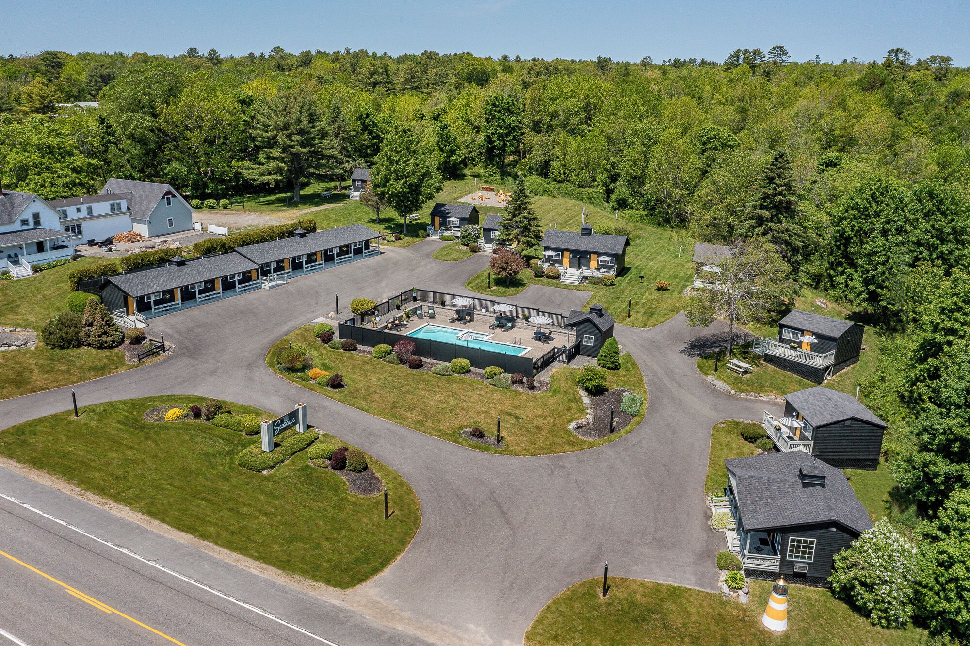 Vue aérienne d’un complexe hôtelier comprenant une piscine, des maisons d’hôtes et une route.