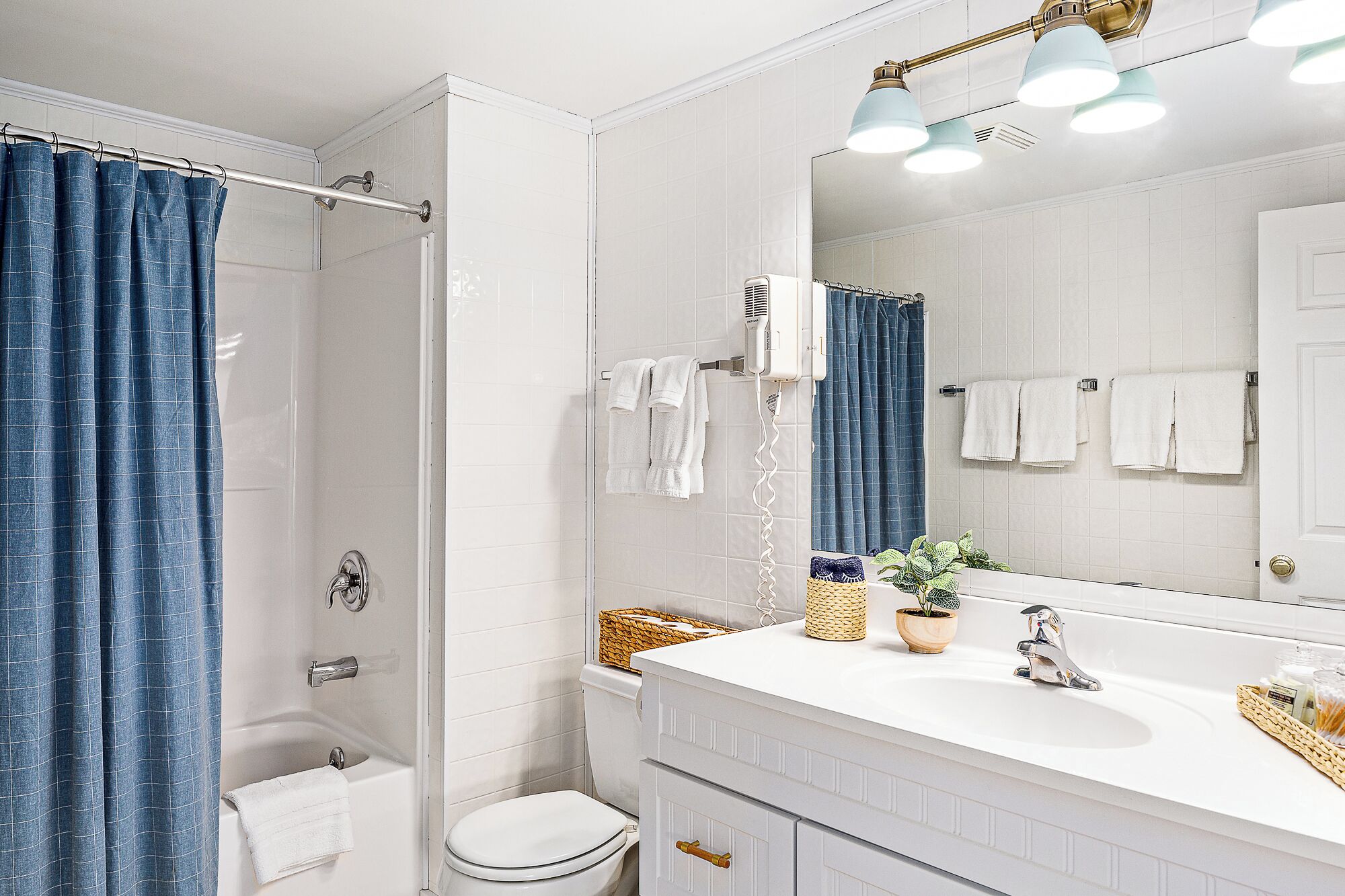 A bathroom with a shower, a toilet, a sink with a mirror, and a towel rack.