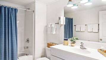 A bathroom with a shower, a toilet, a sink with a mirror, and a towel rack.