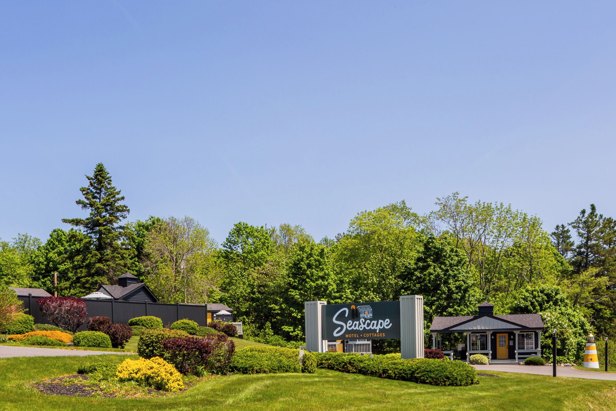 A Seascape motel and cottages with a large sign, surrounded by well-maintained lawns and trees.