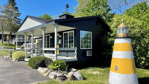 A black building with a porch, a lighthouse, and a clear blue sky. - Seascape Motel & Cottages (Belfast)