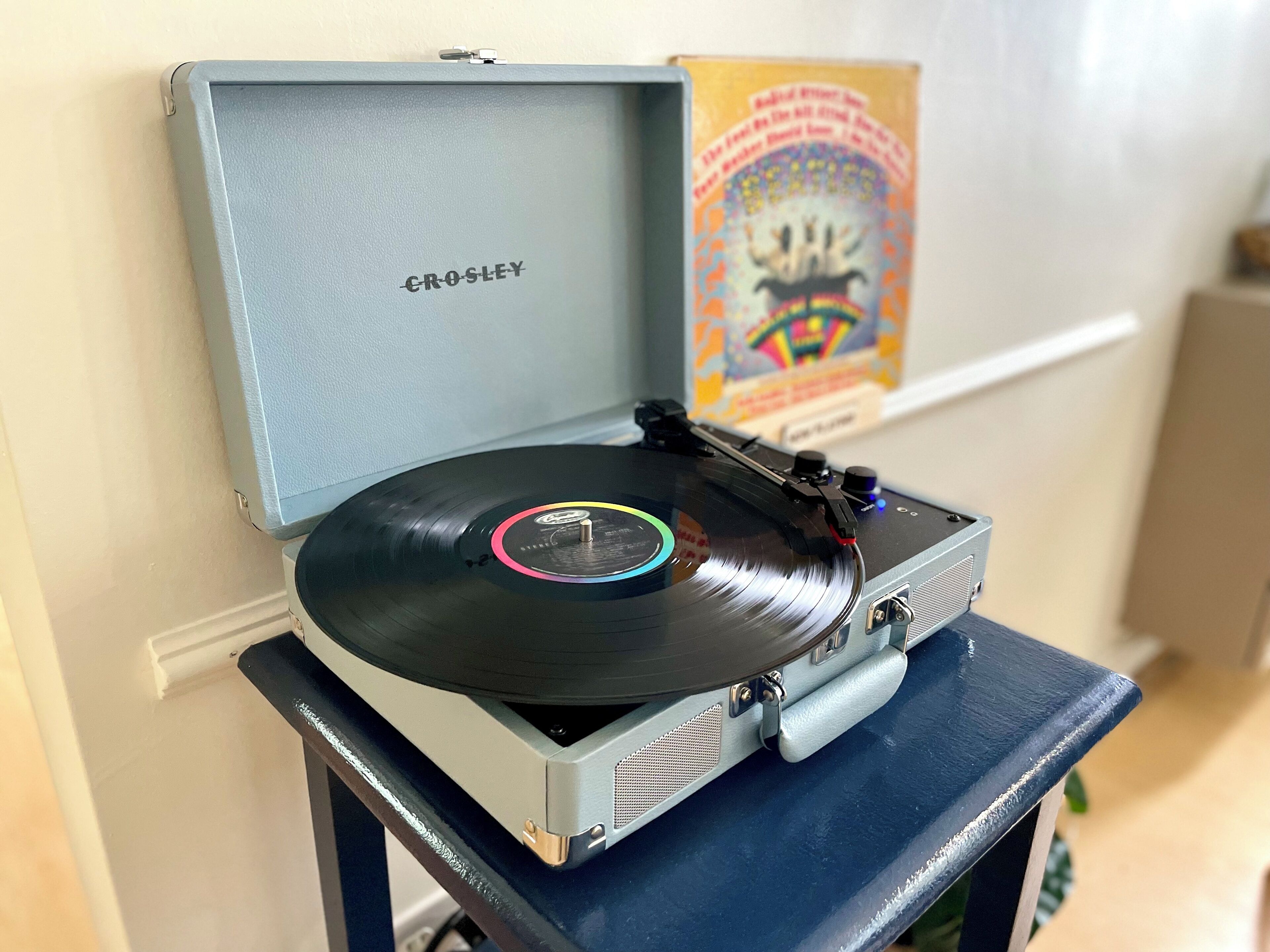 A Crosley turntable with a vinyl record on a blue stand.