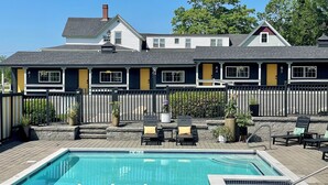 A hotel with a swimming pool, outdoor seating, and a fenced patio area. - Seascape Motel & Cottages (Belfast)