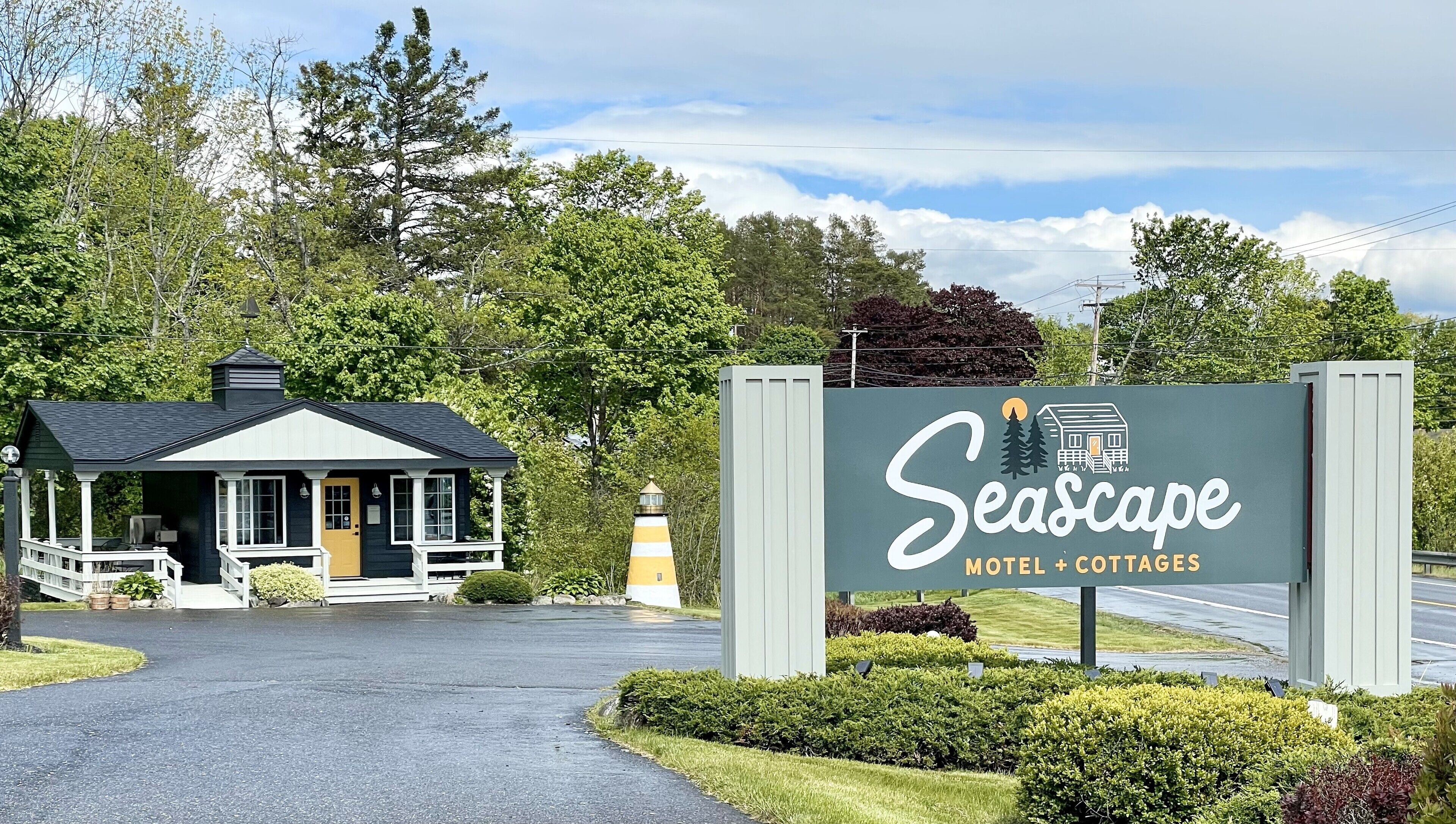 A Seascape Motel & Cottages sign with a lighthouse in the background.