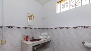 Een badkamer met een marmeren wastafel, een spiegel en een toiletrolhouder.