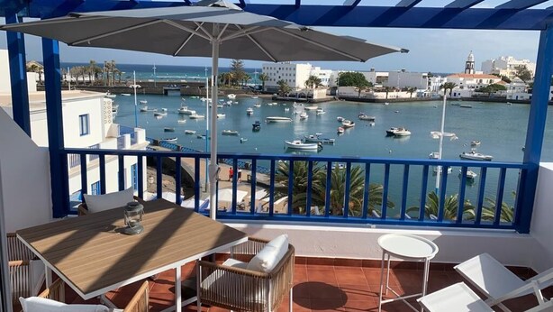 Un balcón con vistas a un puerto deportivo, que incluye una mesa, sillas y una sombrilla.