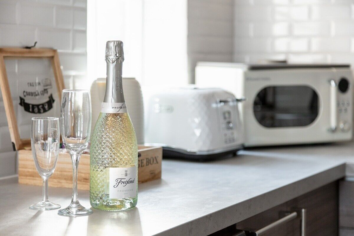 A kitchen with a bottle of Freixenet champagne, two glasses, and a toaster.