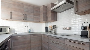 Una cocina moderna con armarios de madera, salpicadero de azulejos blancos y electrodomésticos de acero inoxidable.