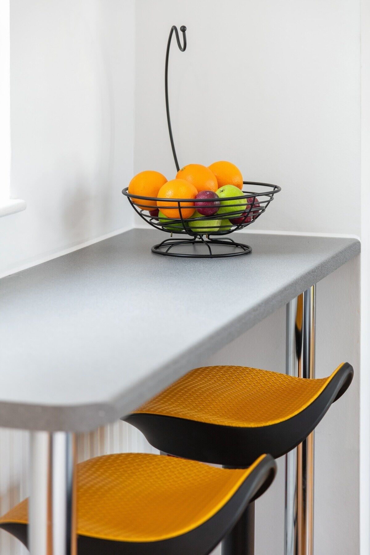 A dining table with a fruit bowl containing oranges, apples, and pears.