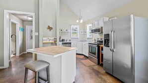 Una cocina moderna con armarios blancos, electrodomésticos de acero inoxidable y una isla central.