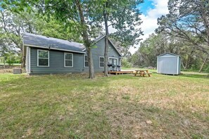 A two-story house with a covered patio and a small shed in a grassy yard. - Zona’s home (Whitney)