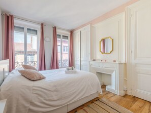 A bedroom with a large bed, a fireplace, and a view of the city.