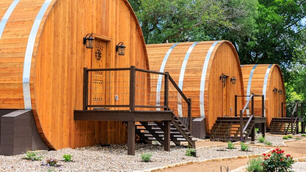 Structures en forme de tonneau, faites de bois, avec des garde-corps et des escaliers en métal menant à l’entrée.