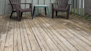 A wooden deck with two Adirondack chairs and a small table, surrounded by a wooden fence.