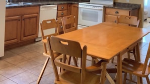 A kitchen with wooden cabinets, a microwave, a stove, and a dining table with chairs.