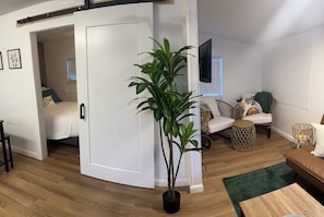 Relax in this spacious living area with a comfortable sofa, flat-screen TV, and natural greenery.