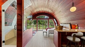 Ein modernes Interieur mit Holzboden, einer Küchenzeile mit Barhocker und Blick ins Freie.