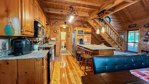Ein Holzblockhaus-Interieur mit Küche, Essbereich und einer Treppe.