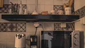 A kitchen with a microwave, a coffee maker, and a trash can.