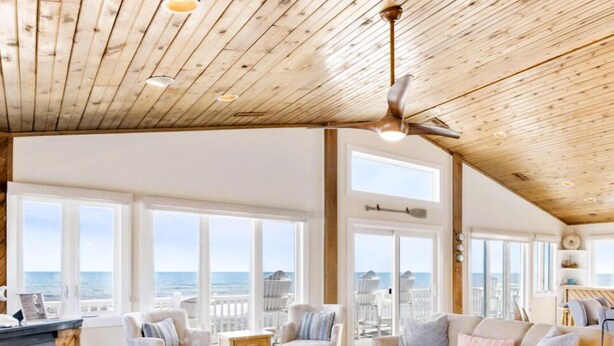 A spacious living room with a high ceiling, large windows, and a view of the ocean. - Oceanfront, Hot Tub, Game Room (Kitty Hawk)