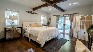 Un dormitorio con una cama grande, vigas de madera, una ventana con lámpara y vistas al exterior.