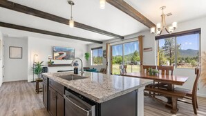 A modern kitchen with a granite countertop, stainless steel appliances, and a dining area with a wooden table and chairs. - Grand Canyon Brand New Home with AC. Near Golf Course, Lake & Bearizona (Williams)