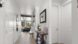 A hallway with white doors, a dining area with a table and chairs, and a decorative vase on a console table. - Grand Canyon Brand New Home with AC. Near Golf Course, Lake & Bearizona (Williams)