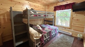 Une chambre avec un lit superposé, une fenêtre et un radiateur.