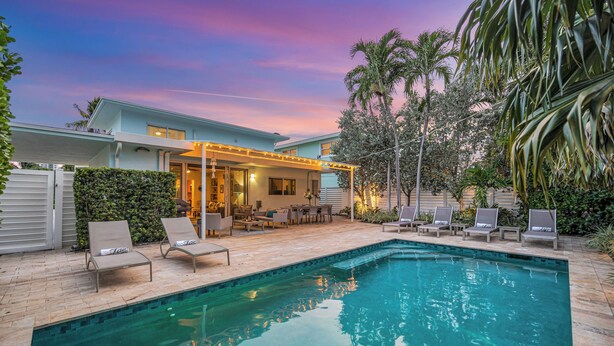 A swimming pool with lounge chairs and a covered patio area. - Steps from Beach | Heated Pool | Gulf Stream Key | RESlDENCES (Fort Lauderdale)