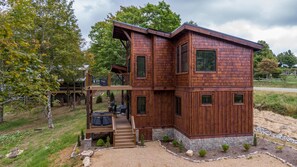 A two-story wooden cabin with a deck and a stone foundation. - Elevated Elk - Million dollar view, hot tub, excellent location! (Banner Elk)
